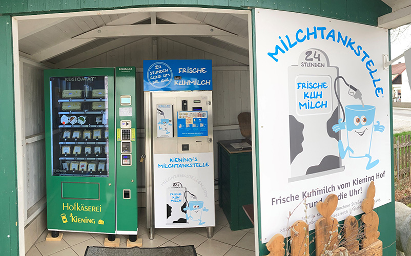 Vorderansicht von einem Hofladen mit Automaten für Käseprodukte und einer Milchtankstelle