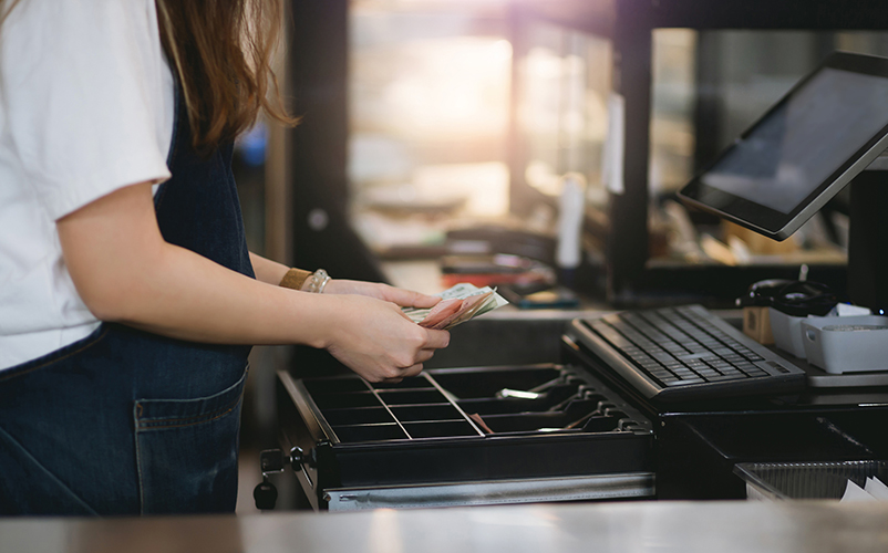 Frau mit Geld in den Händen über eine schwarzen Kasse