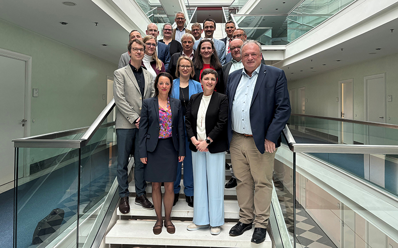 Personengruppe auf einem Treppenaufgang in einem großen Verwaltungsgebäude.